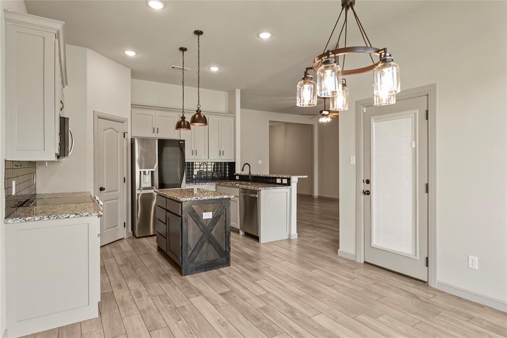 116 Grey Hound Lane Poolville, TX 76487 - Photo 3 of 16 a kitchen with kitchen island granite countertop a refrigerator a sink dishwasher a oven and a dining table with wooden floor