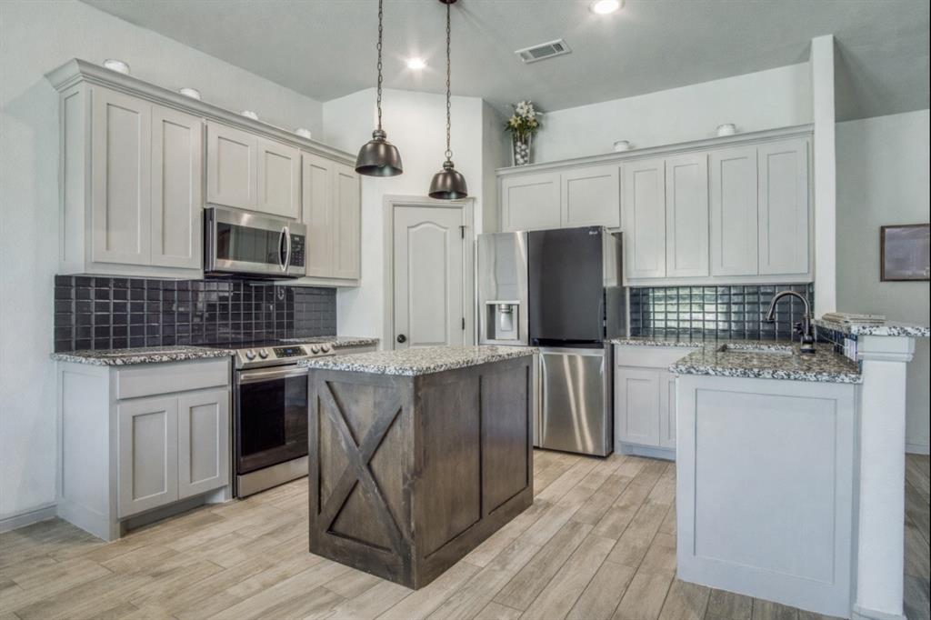 116 Grey Hound Lane Poolville, TX 76487 - Photo 4 of 16 a kitchen with stainless steel appliances granite countertop a stove top oven a refrigerator a sink and white cabinets