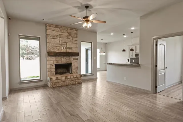 an empty room with wooden floor a kitchen view and a fireplace