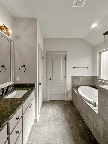a spacious bathroom with a granite countertop tub a double vanity sink and mirror