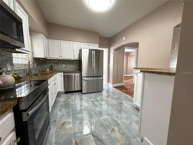 a kitchen with stainless steel appliances granite countertop a refrigerator a stove top oven a sink and dishwasher