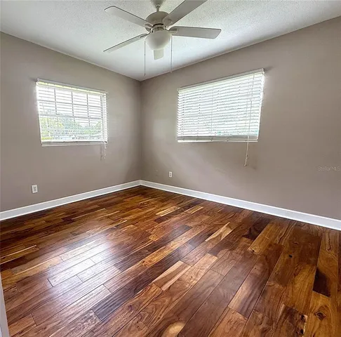 a view of empty room with wooden floor and fan