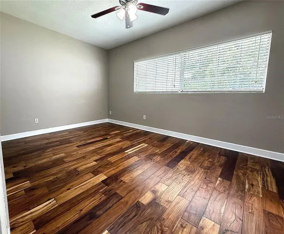 a view of an empty room with wooden floor and a window