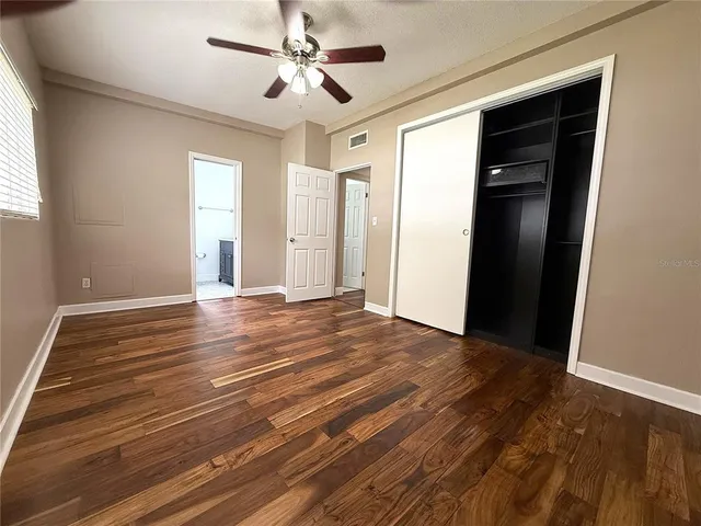 a view of empty room with wooden floor and fan