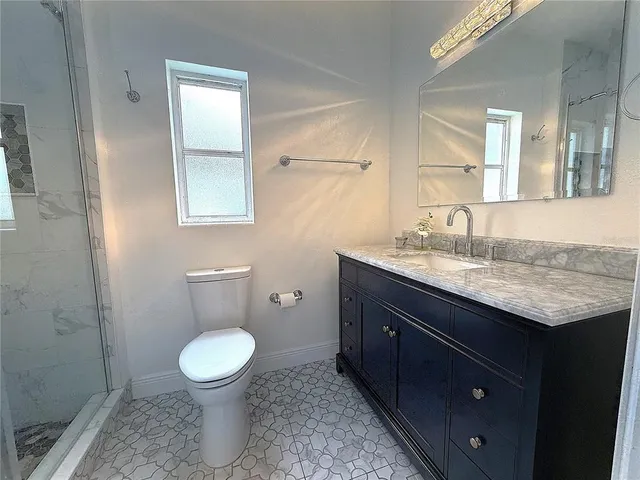 a bathroom with a granite countertop toilet sink and mirror