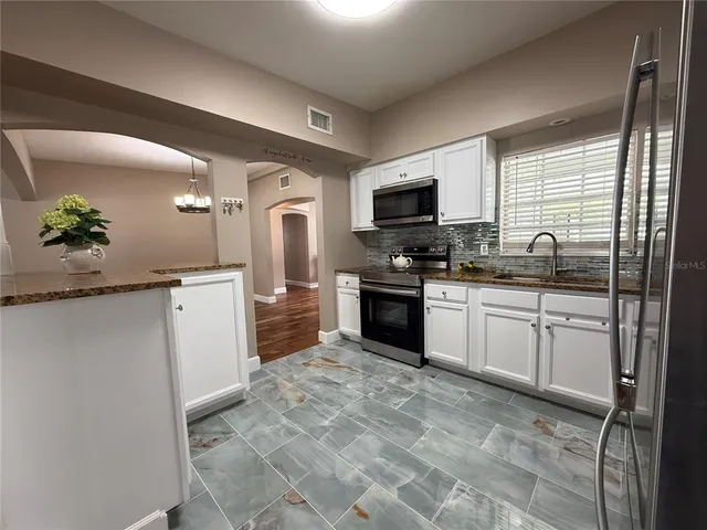 a kitchen with granite countertop a sink a counter top space appliances and cabinets