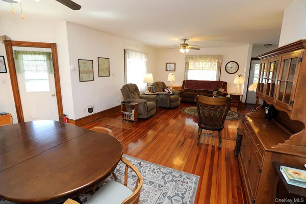 a living room with dining room furniture wooden floor and a rug