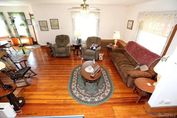 a living room with couches chairs and a dining table with wooden floor