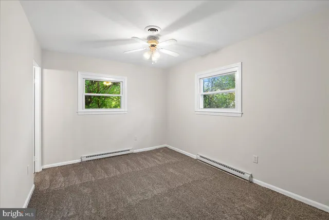 an empty room with windows and fan