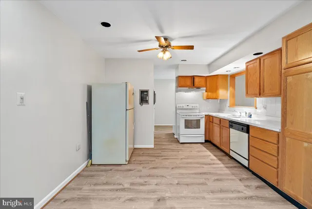 a large kitchen with stainless steel appliances a large counter top a sink and a refrigerator