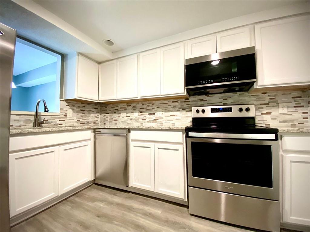 5840 Par Four Court Lithonia, GA 30038 - Photo 7 of 27 a kitchen with stainless steel appliances a stove a microwave sink and cabinets
