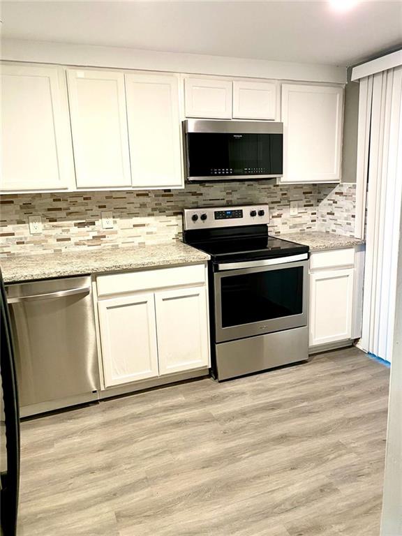 5840 Par Four Court Lithonia, GA 30038 - Photo 8 of 27 a kitchen with stainless steel appliances a stove a microwave and white cabinets