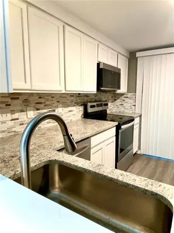 a kitchen with stainless steel appliances granite countertop a stove a sink and a microwave