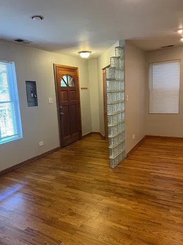 a view of an empty room with window and wooden floor