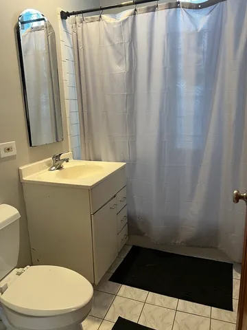 a bathroom with a sink a toilet a mirror and shower curtain