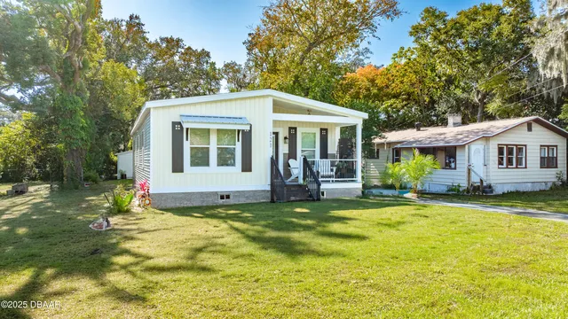 a view of a house with a yard and large tree