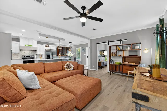 a living room with furniture kitchen view and a large window