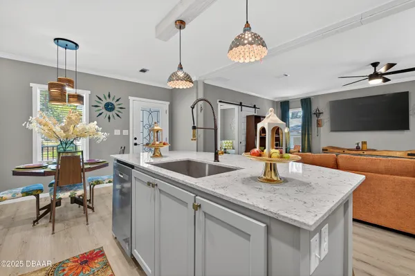 a kitchen with a stove a sink dishwasher a dining table and chairs with wooden floor