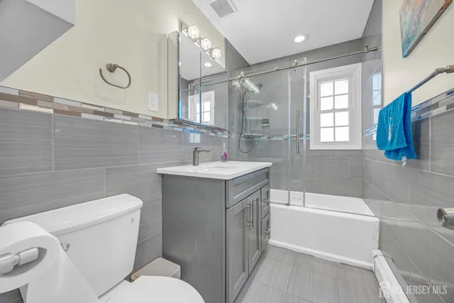 a bathroom with a sink vanity mirror bathtub and toilet