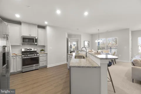 a kitchen with kitchen island granite countertop a sink cabinets and stainless steel appliances