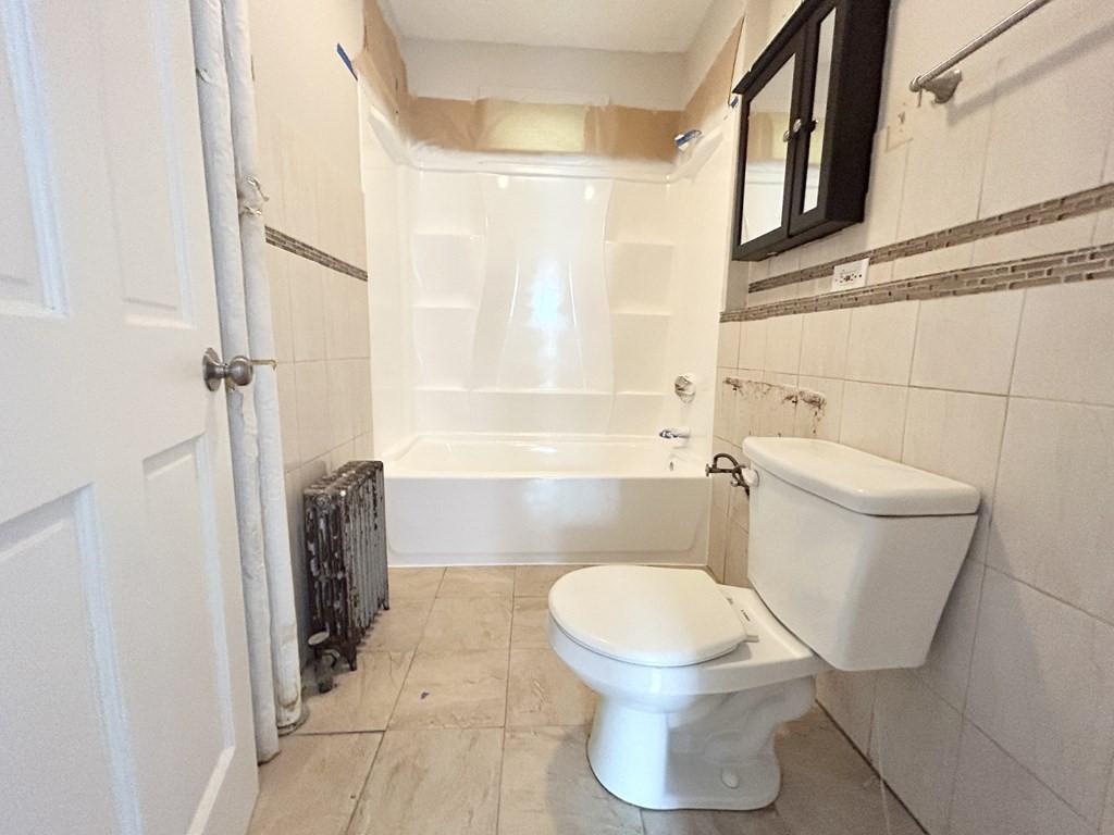 22 Humphreys Street, Unit 1 Boston, MA 02125 - Photo 6 of 6 a white toilet sitting next to a bathroom sink and a shower