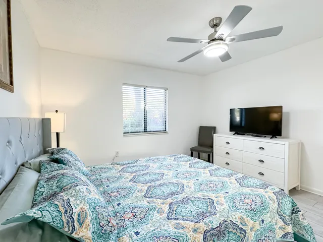 a bedroom with a bed a chandelier and a television