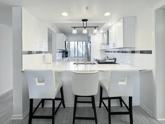 a kitchen with stainless steel appliances a table chairs refrigerator and sink