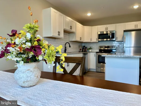 a kitchen with stainless steel appliances granite countertop a refrigerator a stove a sink dishwasher and a microwave with wooden floor