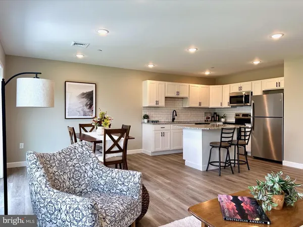 a kitchen with stainless steel appliances granite countertop a refrigerator a stove a sink a dining table and chairs