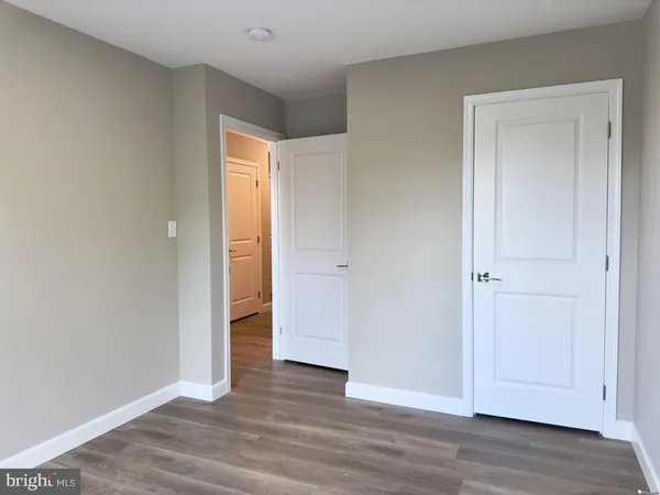 a view of an empty room with wooden floor and closet