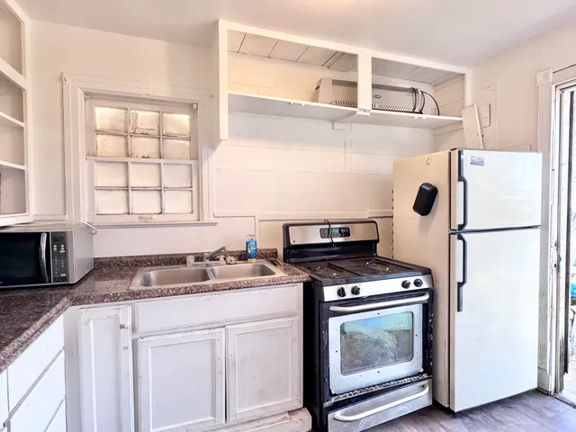 a kitchen with granite countertop a sink cabinets and stainless steel appliances