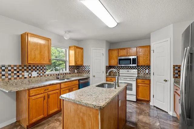 a kitchen with stainless steel appliances granite countertop a sink stove and refrigerator