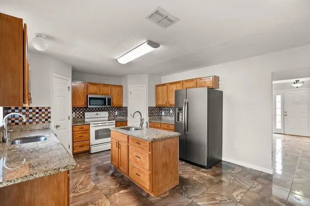 a kitchen with stainless steel appliances granite countertop a refrigerator stove and sink