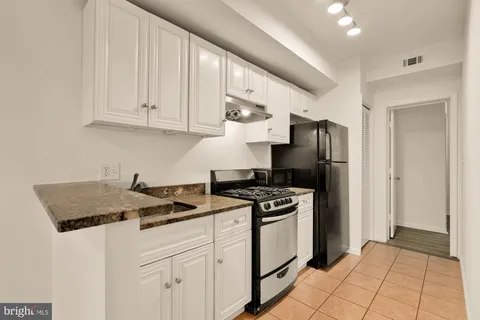 a kitchen with stainless steel appliances granite countertop a stove a refrigerator and a white cabinets