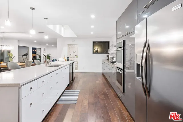 a large kitchen with kitchen island a counter top space a sink a refrigerator and a view of living room