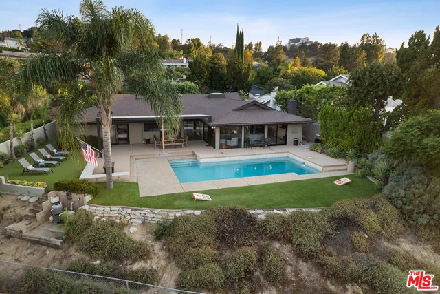 a view of a house with swimming pool next to a yard