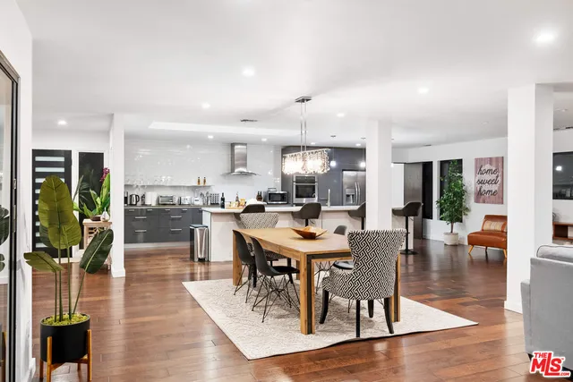 a dining hall with stainless steel appliances kitchen island granite countertop a dining table chairs and a living room view