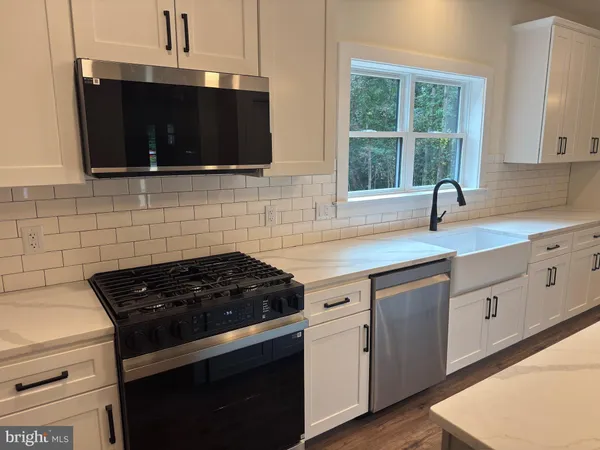 a kitchen with granite countertop a stove a sink and a microwave