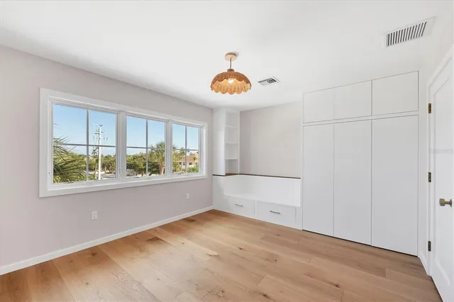 a view of an empty room with wooden floor and windows