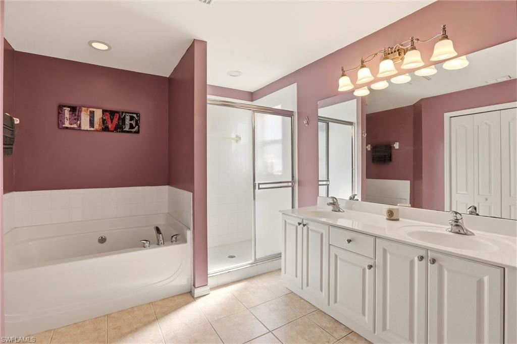 21524 Windham Run Estero, FL 33928 - Photo 35 of 50 a bathroom with a bathtub a double vanity sink and a mirror