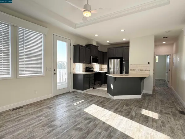 a view of kitchen with stainless steel appliances granite countertop a refrigerator a sink dishwasher a stove with wooden cabinets and floor