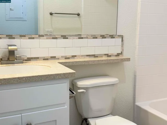 a bathroom with a granite countertop toilet sink and mirror