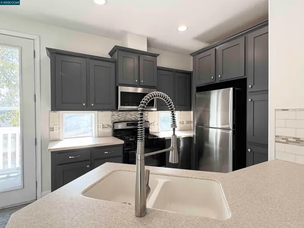 a kitchen with granite countertop a refrigerator and a stove top oven