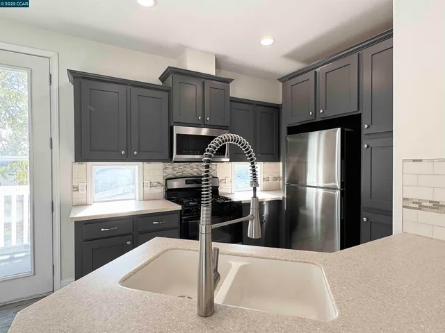 a kitchen with granite countertop a refrigerator and a stove top oven