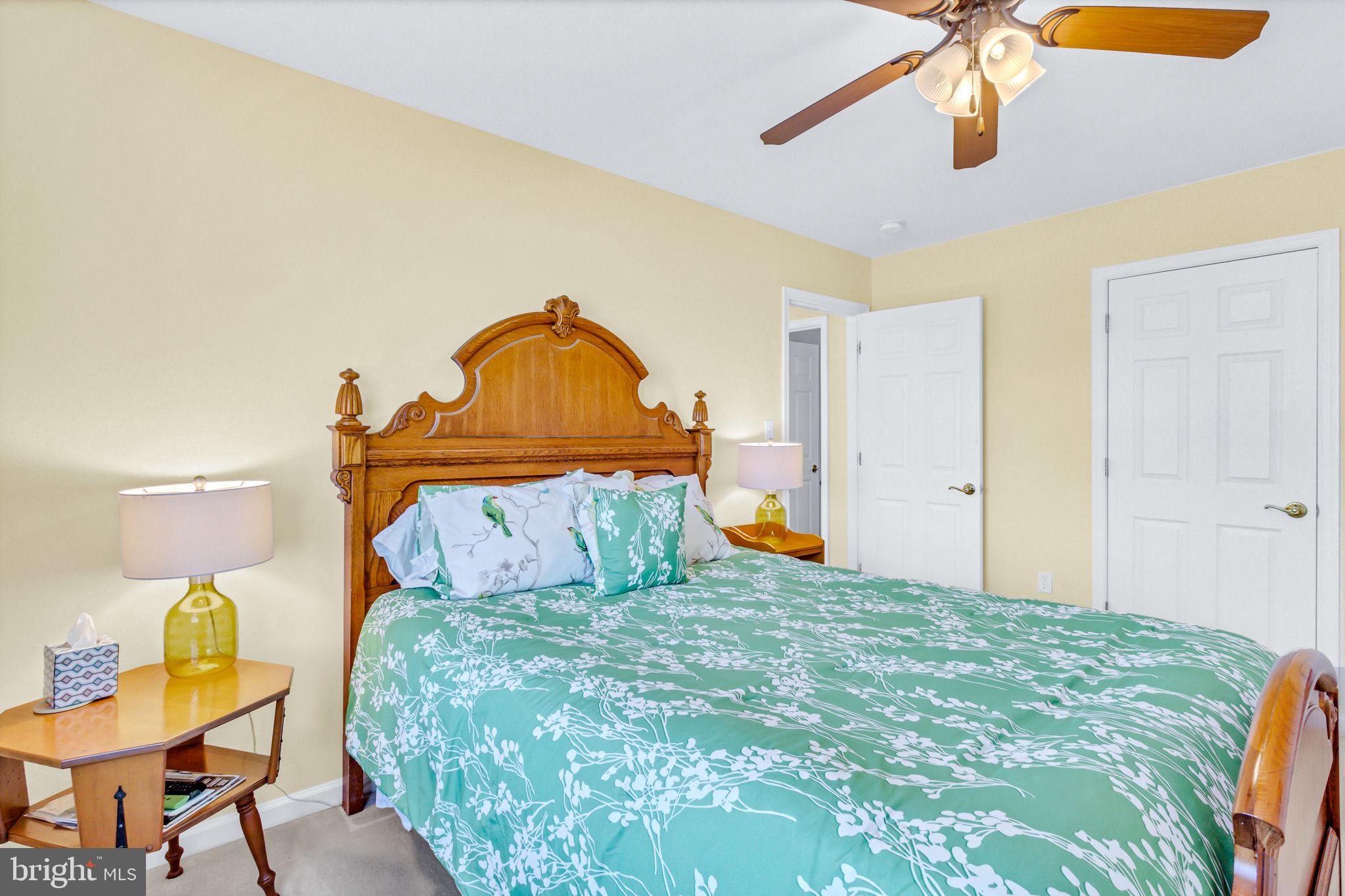 88 Old Field Road Irvington, VA 22480 - Photo 44 of 55 a bedroom with a bed a lamp on dresser and a chandelier
