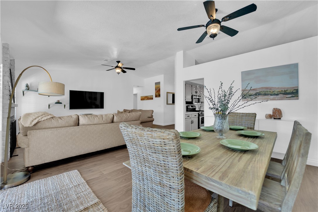 Dining/great room with ceiling fan, light wood finished floors, and Vaulted ceilings