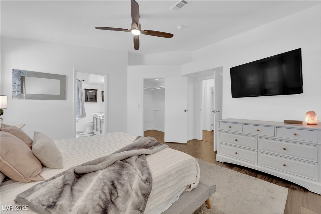 148 Triberg Court Henderson, NV 89074 - Photo 14 of 27 Primary bedroom with ceiling fan, ensuite bath, wood finished floors, a spacious closet, and vaulted ceilings.