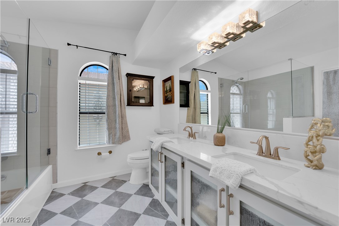 148 Triberg Court Henderson, NV 89074 - Photo 16 of 28 Primary bath featuring double quartz vanity, toilet, enclosed tub / shower combo, and french door to back covered patio.