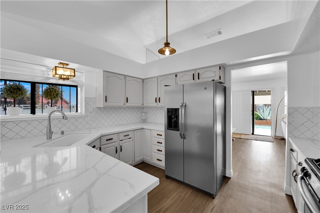 148 Triberg Court Henderson, NV 89074 - Photo 10 of 27 Kitchen with light calcutta quartz stone counters, farm sink, stainless steel appliances, decorative backsplash, and visible vents