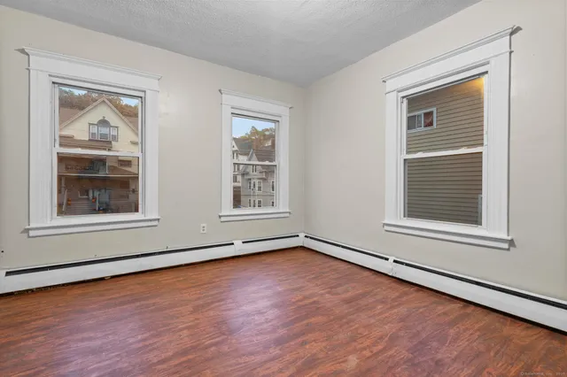 a view of an empty room with wooden floor and a window